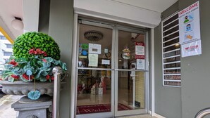 A hotel entrance with a glass door, a welcome sign, and a hand sanitizer sign.