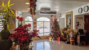 A spacious lobby with a large Christmas tree, a reception desk, and a bulletin board.