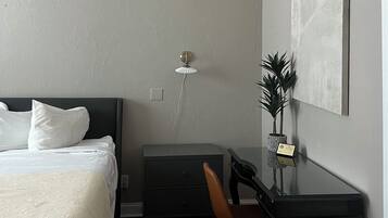 Un dormitorio con cama, escritorio, silla, radiador y ventilador de techo.