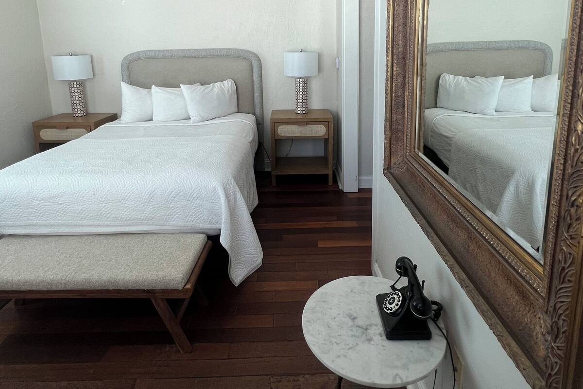 A hotel room with two beds, a ceiling fan, a round table, and a large mirror.