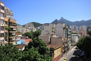 A cityscape with multi-story buildings, a street, and a mountain in the background. - Baependi 503 (Rio de Janeiro)