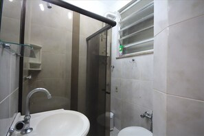 A bathroom with a glass-enclosed shower, a white sink, and a toilet. - Baependi 503 (Rio de Janeiro)