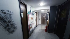 A hallway with a fire extinguisher, a door with a sign, and a wall with a poster. - Tempo Inn West Kowloon HSR Station (Kowloon)