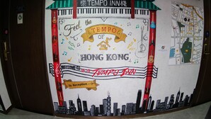 A wall mural with a cityscape and a sign that reads "Feel the TEMPO of HONG KONG" at a hotel entrance. - Tempo Inn West Kowloon HSR Station (Kowloon)