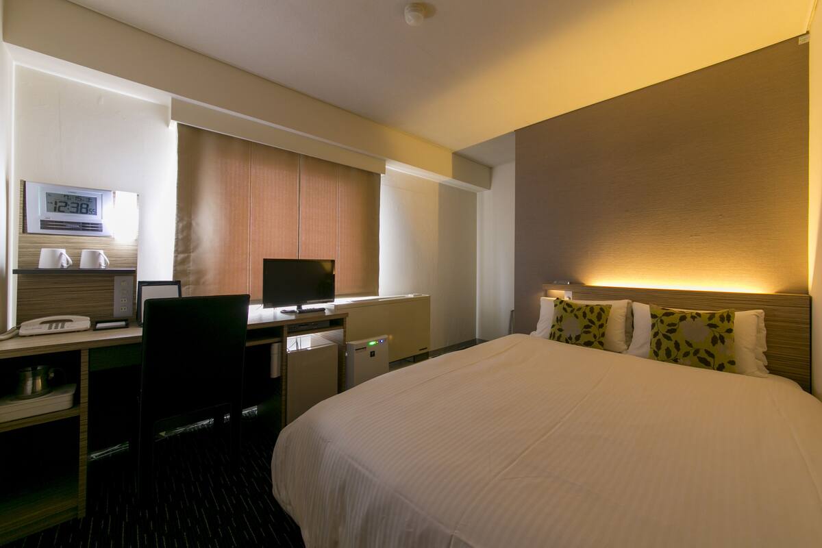 Une chambre d’hôtel avec un lit, un bureau et une télévision.