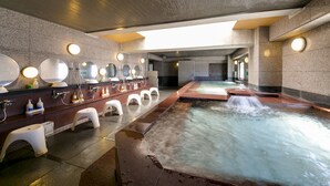 Een modern binnenspacentrum met een whirlpool, meerdere wastafels met spiegels en een natte vloer.
