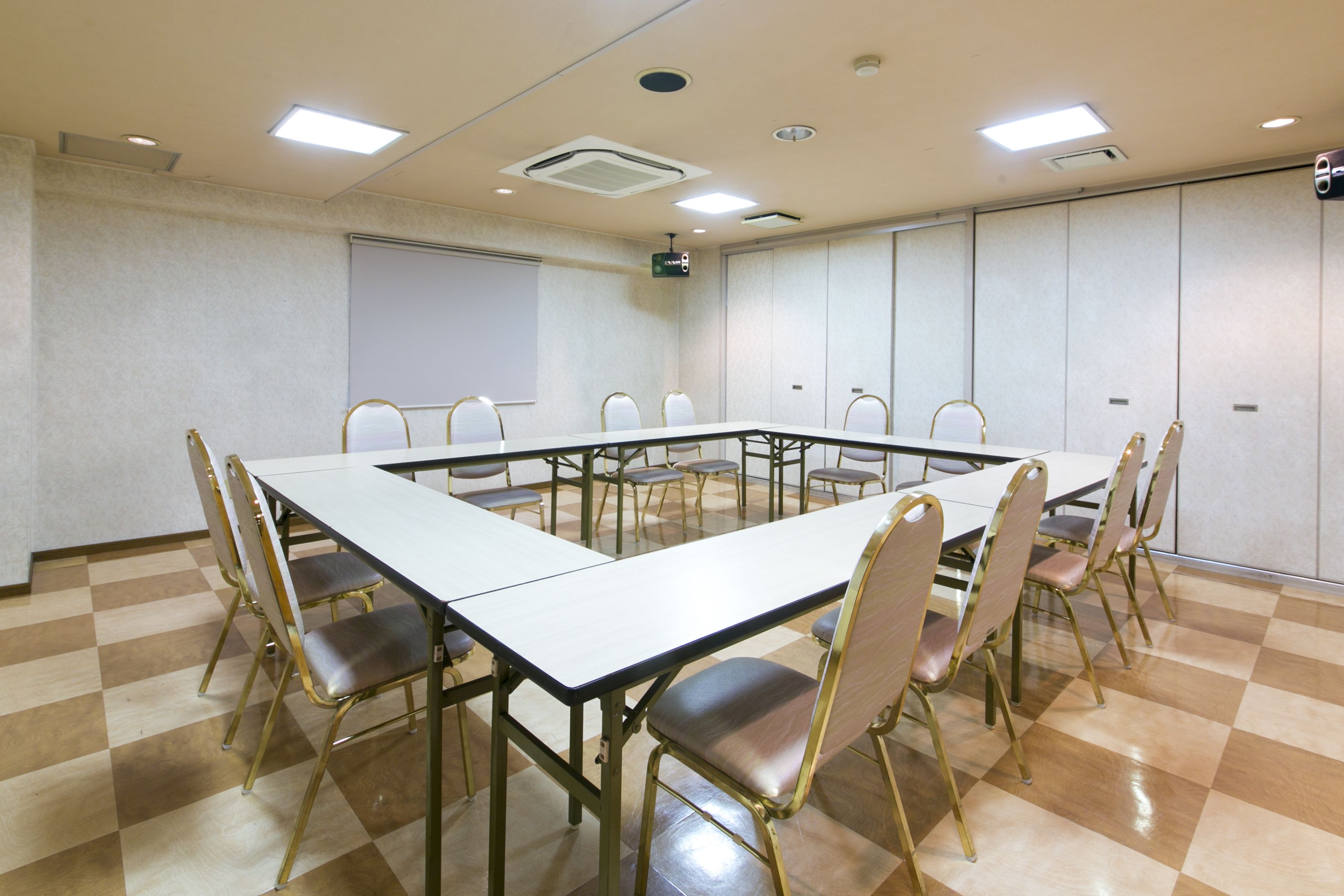 A conference room with a long table, chairs, a projector screen, and a whiteboard.