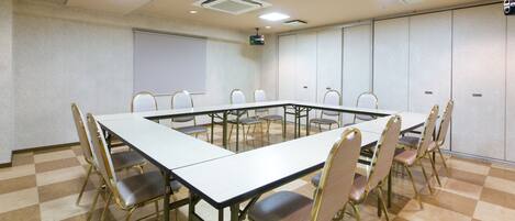 A conference room with a long table, chairs, a projector screen, and a whiteboard.