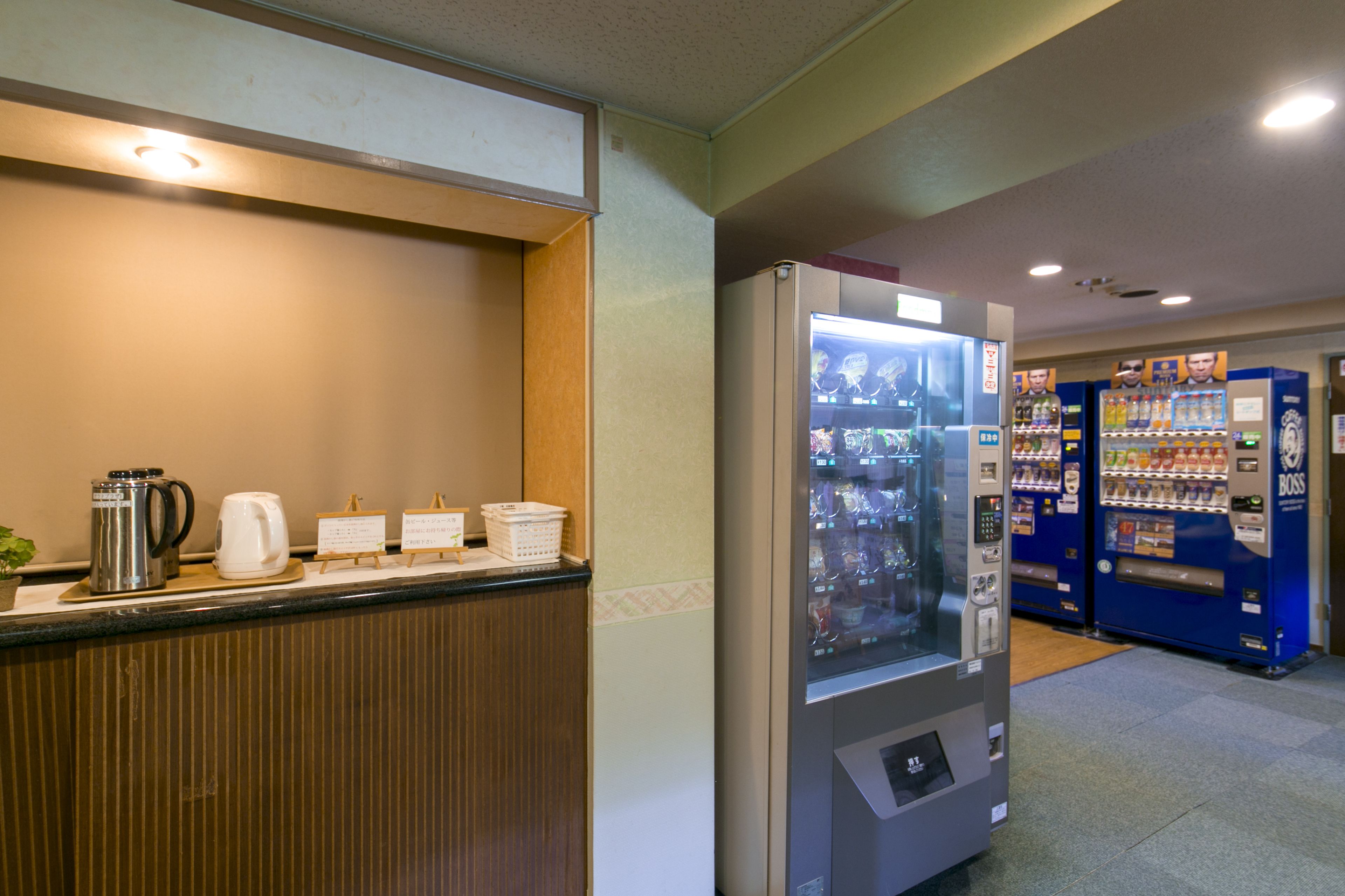 A hotel reception area with a coffee station, vending machines, and a counter with a plant.