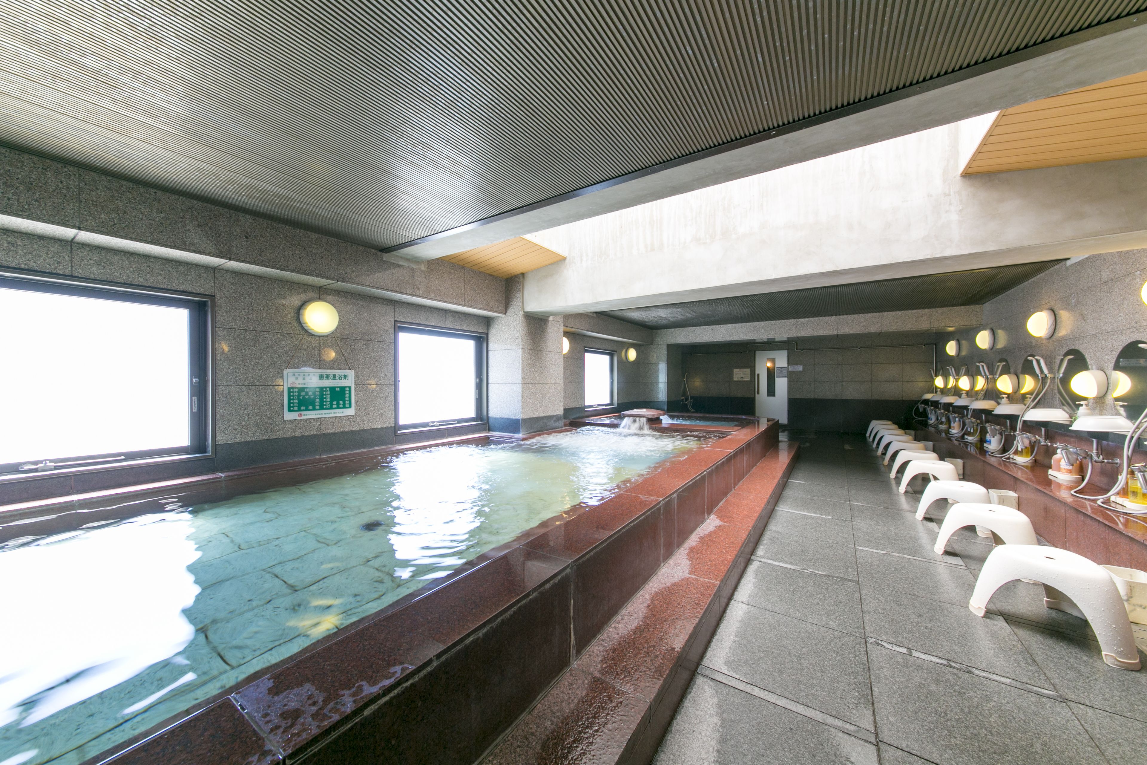 A swimming pool with a long bench area and multiple mirrors.