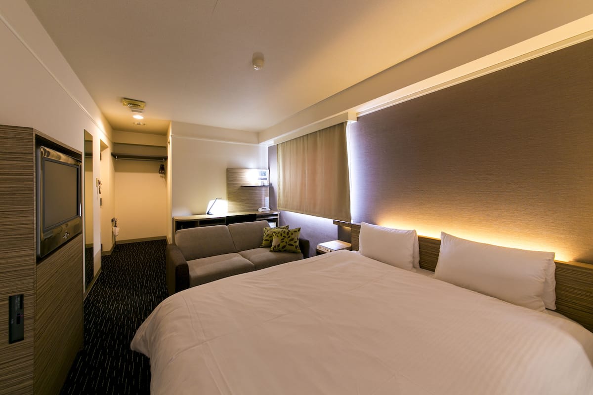 Une chambre d’hôtel avec un grand lit, un canapé, un bureau et une télévision.