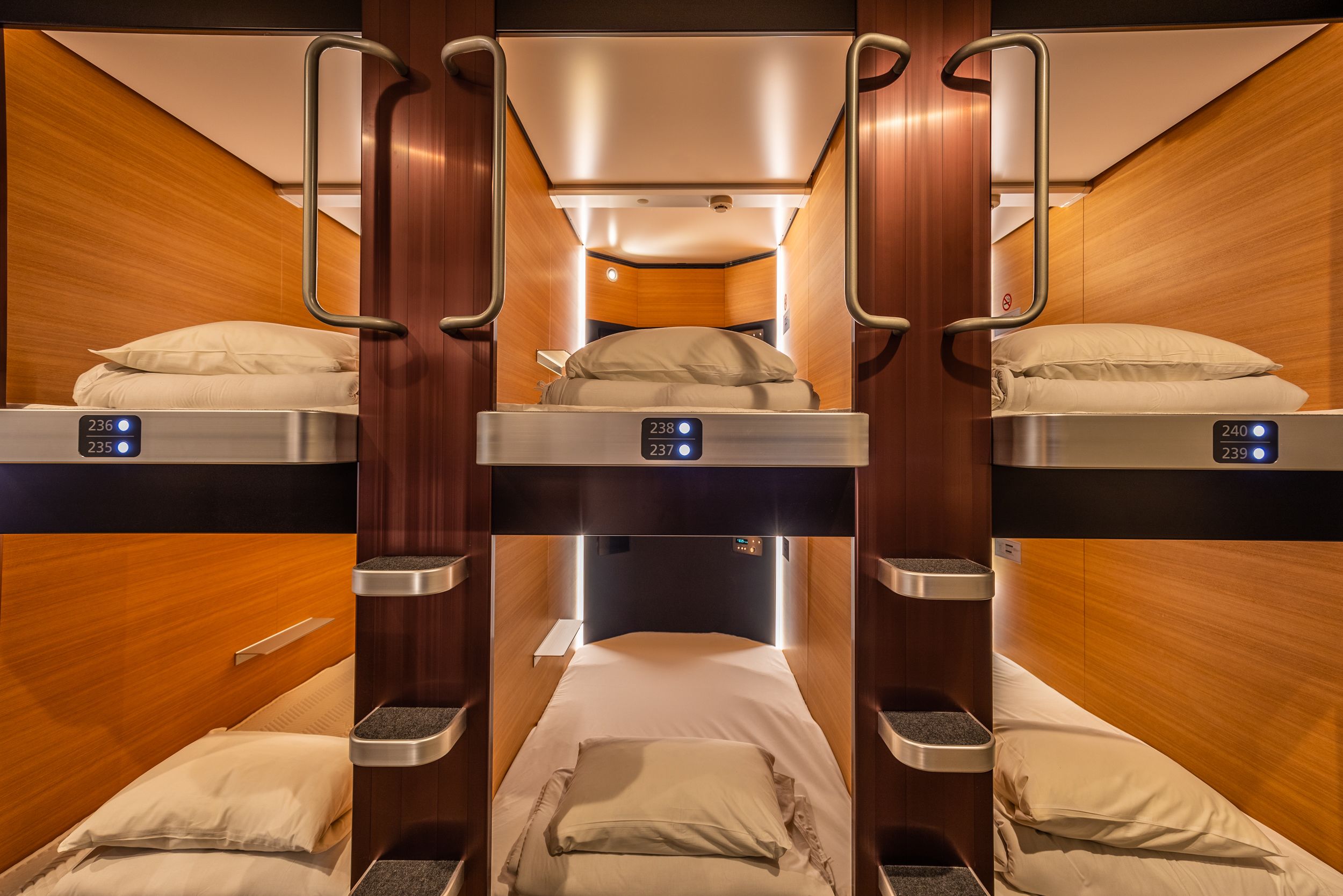A train cabin with three bunk beds, each with a digital display showing room numbers.