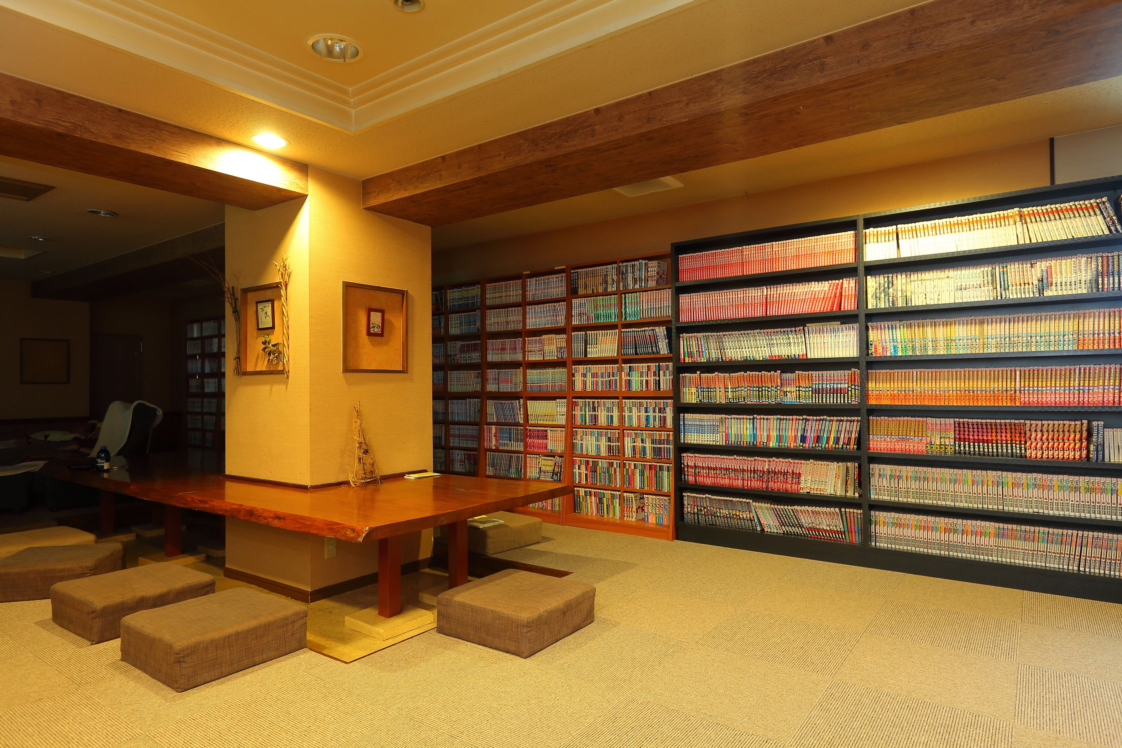 Una biblioteca con una mesa de madera y asientos acolchados, rodeada de estanterías llenas de libros.