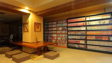Una biblioteca con una mesa de madera y asientos acolchados, rodeada de estanterías llenas de libros.