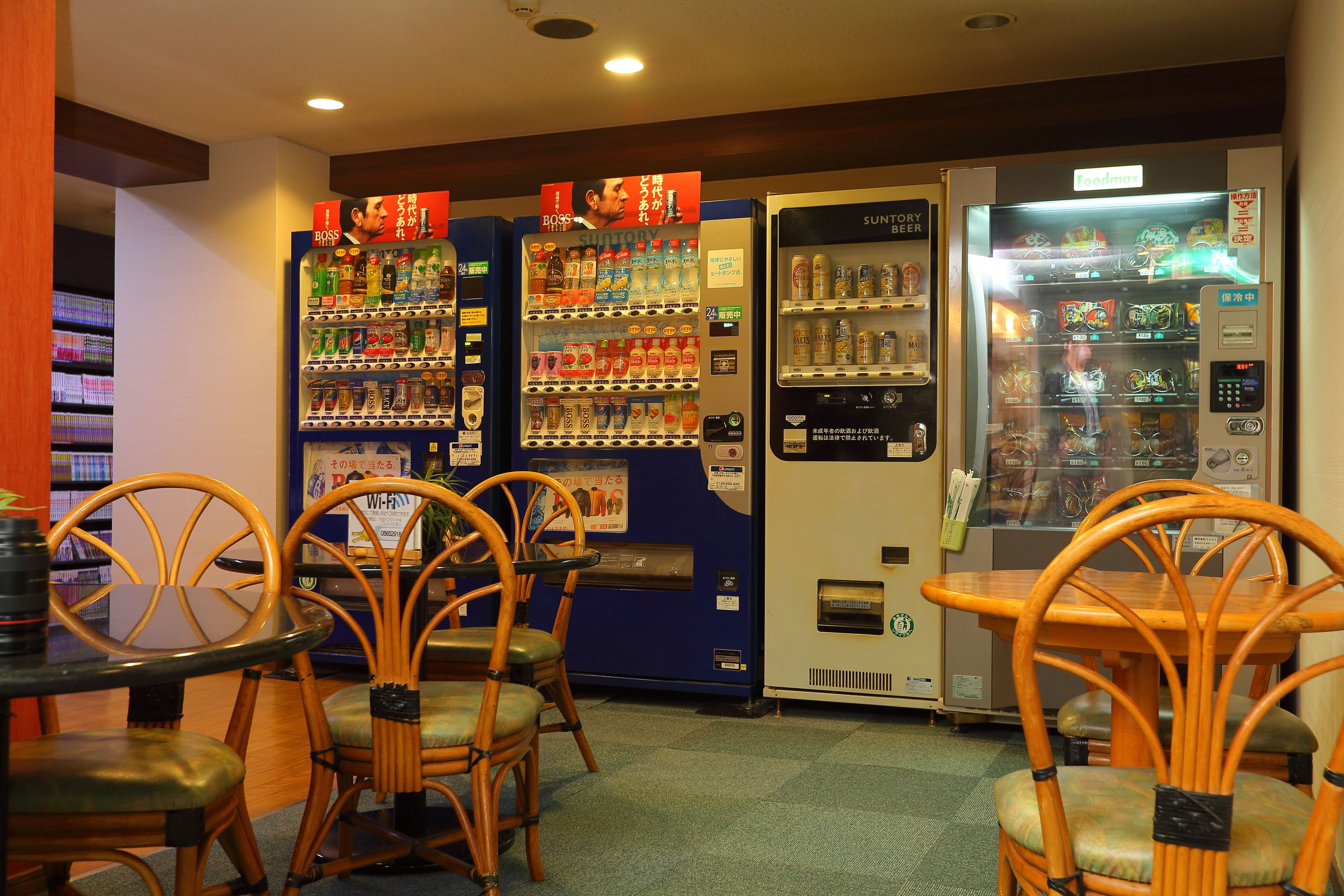 A restaurant interior with vending machines, wooden chairs, and tables.