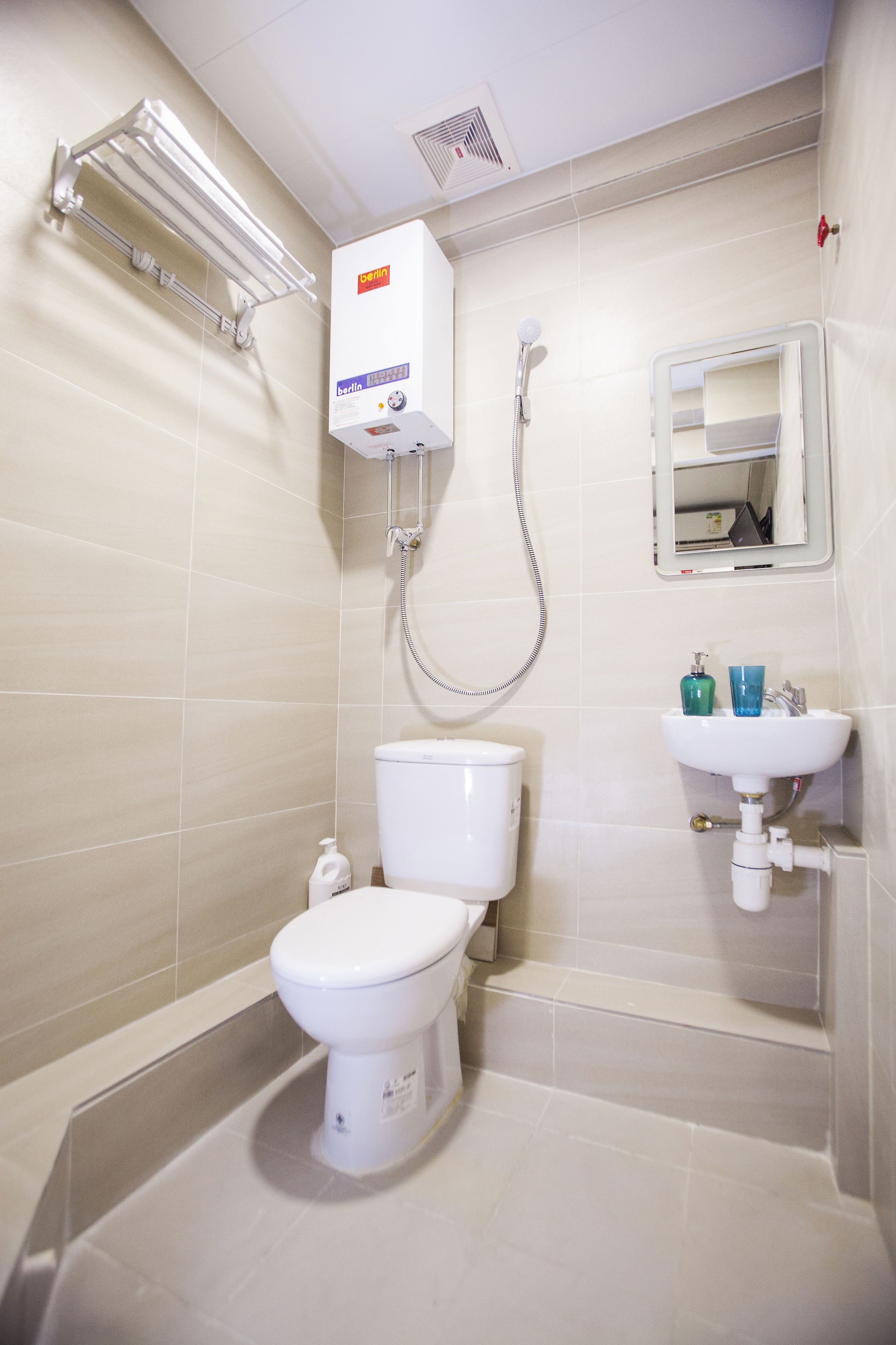 A bathroom with a toilet, a sink, a mirror, and a shower.