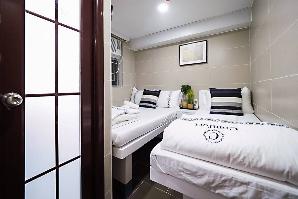 A hotel room with two beds, a framed picture on the wall, and a small plant on the nightstand.