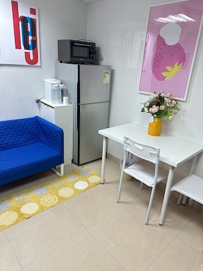 A compact kitchenette with a microwave, refrigerator, and a small table with a vase of flowers.