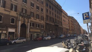 Straßenansicht mit historischen Gebäuden, parkenden Autos und einem Motorrad.