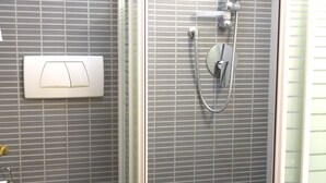 Ein Badezimmer mit Toilette, einer Dusche mit Glastür und einem Handtuch auf dem Toilettendeckel.