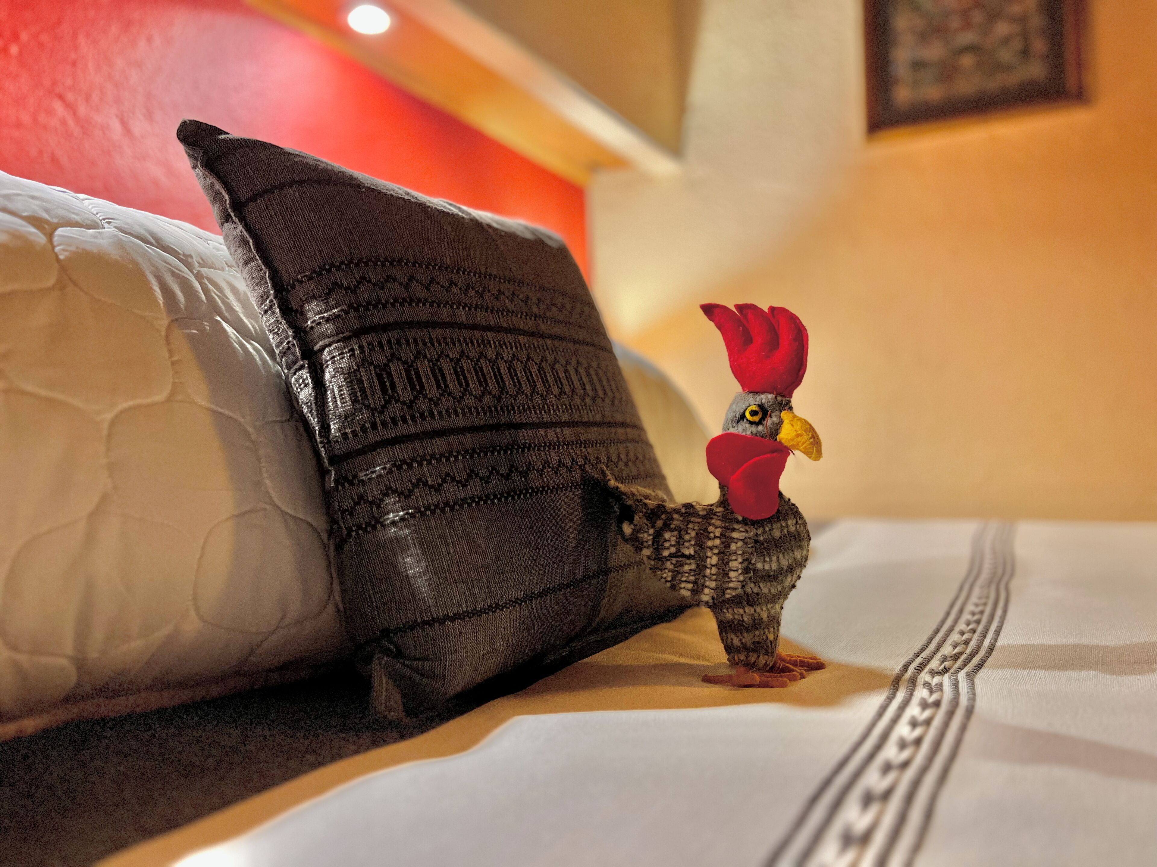 A bed with a pillow and a decorative rooster figure.