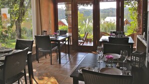 Un espace repas avec des tables et des chaises, de grandes fenêtres et une vue sur la verdure et les bâtiments.