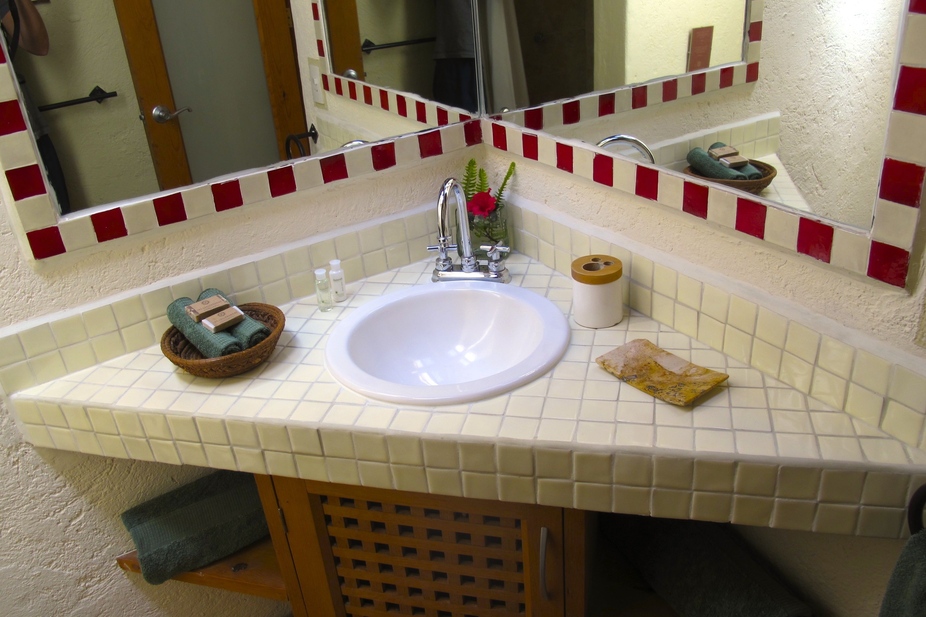 A bathroom with a white sink, a mirror, and a red and white tiled backsplash.