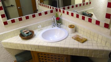 A bathroom with a white sink, a mirror, and a red and white tiled backsplash.