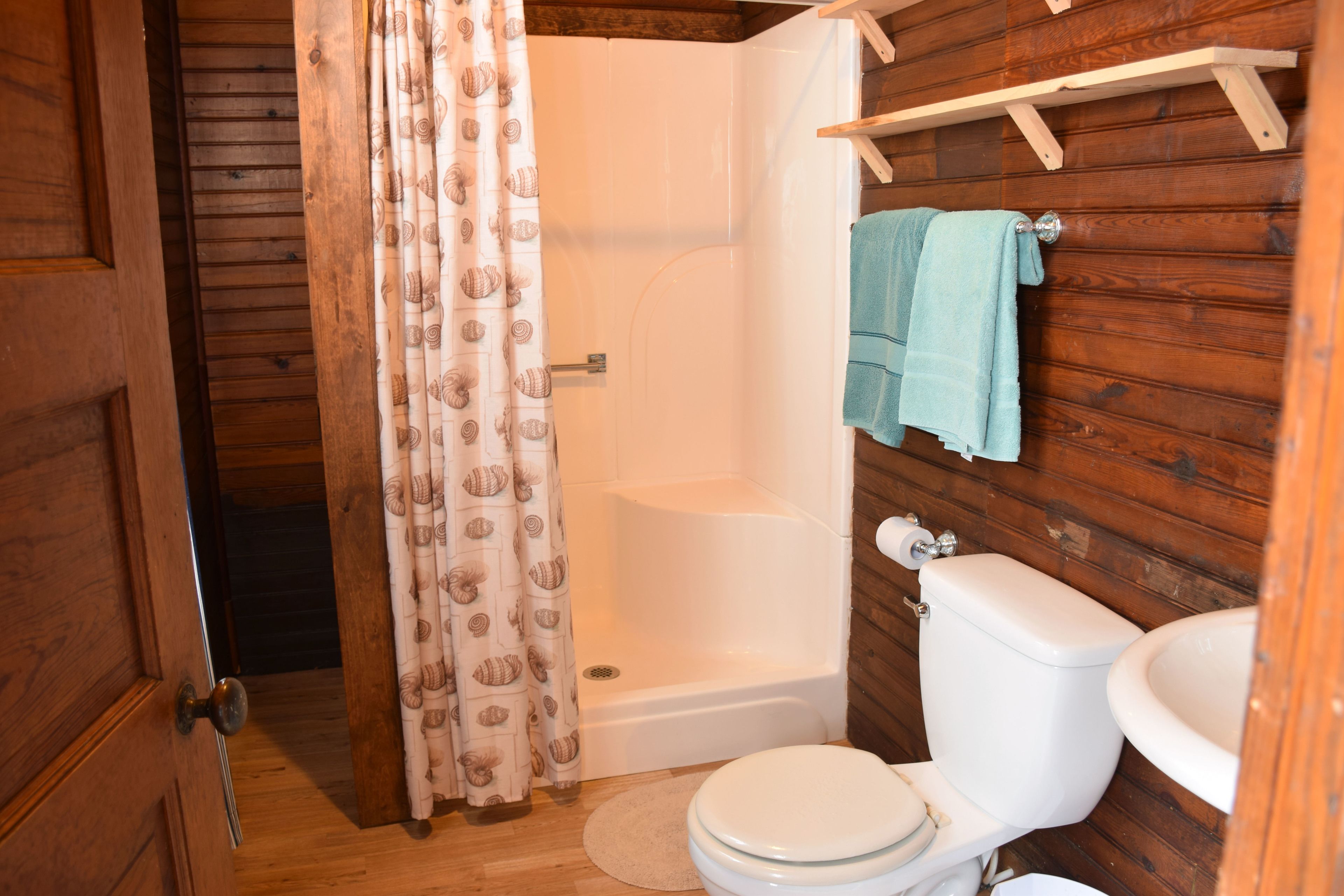 Une salle de bain en bois équipée d’une douche, de toilettes et d’un lavabo.