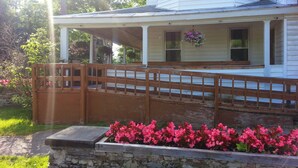 A house with a covered porch, a stone retaining wall, and a wooden fence. - The Baseball Hotel (Richfield Springs)