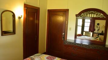 A bedroom with a wooden dresser, a mirror, and a quilted bedspread.