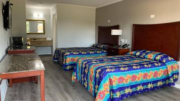 A hotel room with two beds, a desk, a television, a mirror, and a bathroom visible in the background.