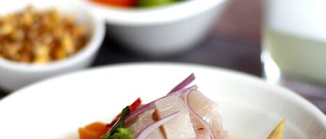 A bowl of seafood soup garnished with vegetables and herbs.