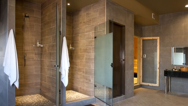 Un bagno moderno con doccia vetro, un lavabo con specchio e pavimento piastrellato.