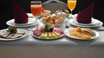 A breakfast table with plates of food, glasses of orange juice, and napkins.