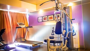 Un gimnasio con cinta de correr, banco de pesas y diversas máquinas de ejercicio.