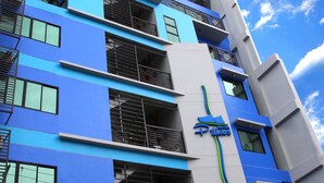 Un hotel con fachada azul y blanca, varios balcones y un letrero que indica que es un hotel.