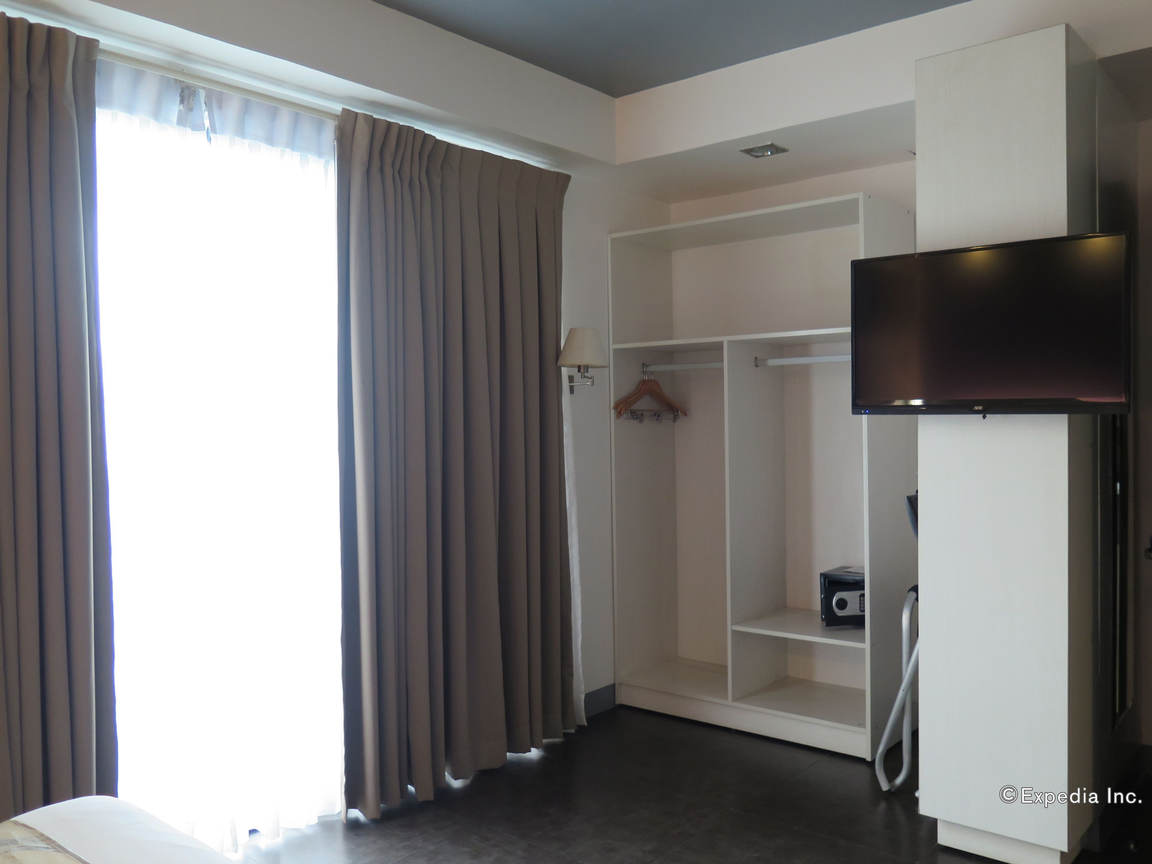 A hotel room with a walk-in closet, a flat-screen TV, and a desk with a chair.