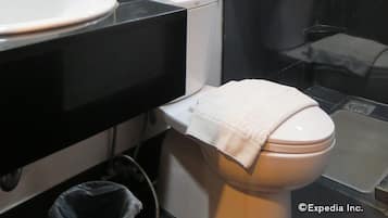 A modern bathroom with a black vanity, a white sink, a toilet, and a mirror.