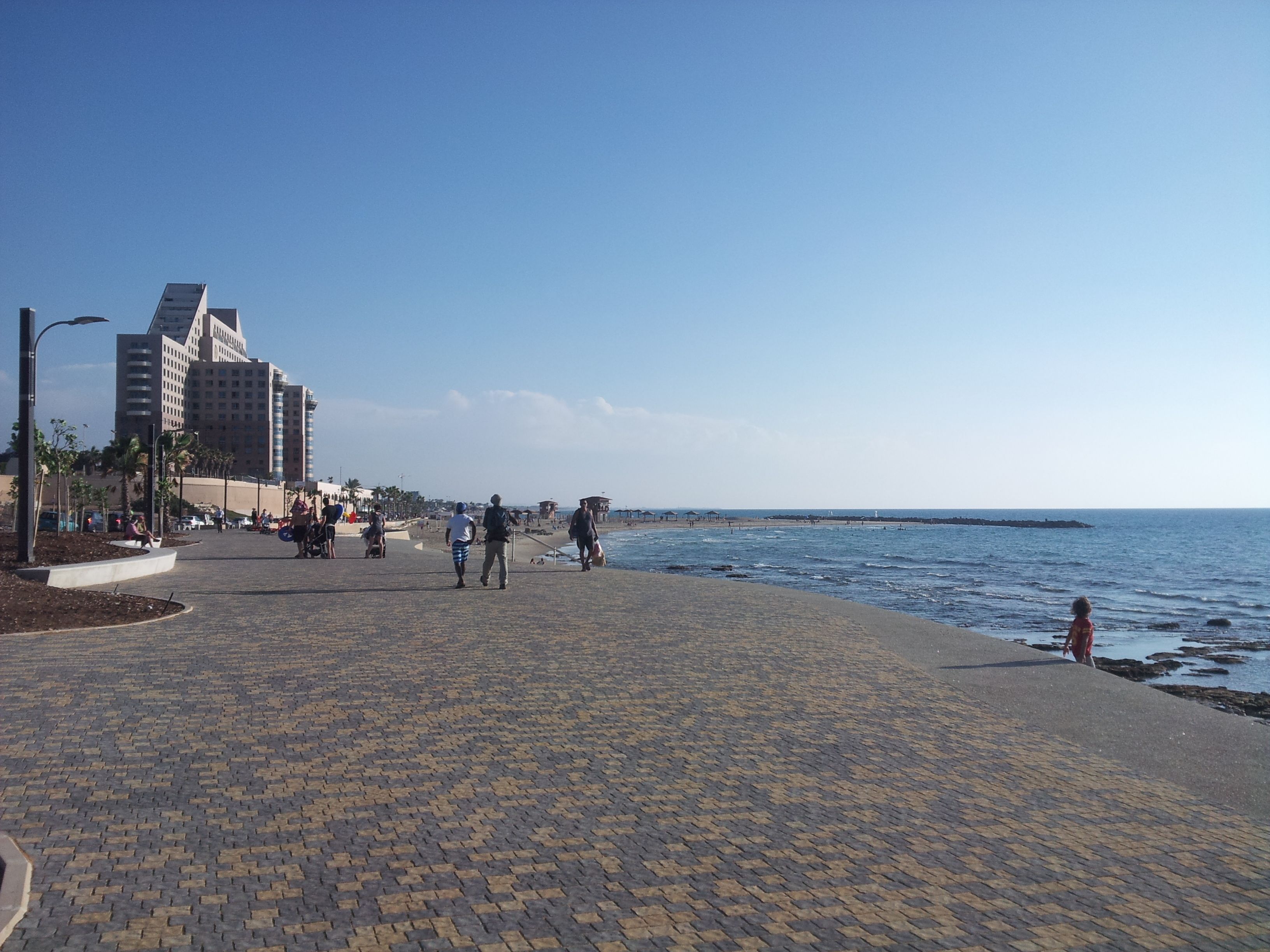 Un paseo marítimo empedrado con vista al mar y edificios al fondo.
