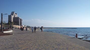 Un paseo marítimo empedrado con vista al mar y edificios al fondo.