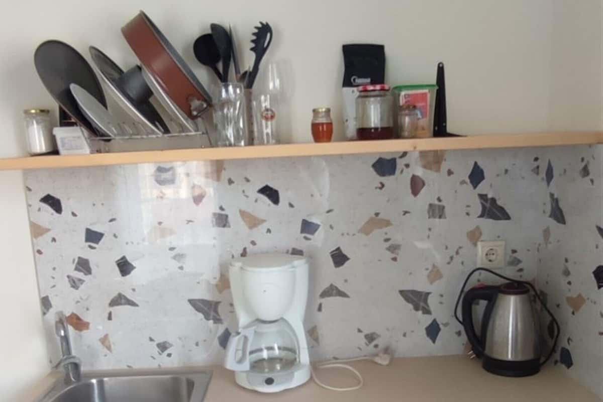A compact kitchen with a sink, a coffee maker, and a kettle on the countertop.