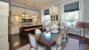 A spacious kitchen with a central island, pendant lighting, and a dining area with a large table and chairs. - All Suites Whitney Manor (Kingston)