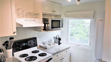 A kitchen with a stove, microwave, and window.