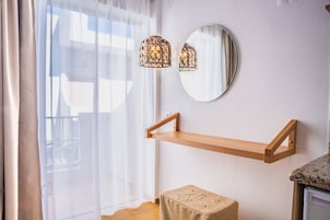 Una habitación con una estantería de madera, un espejo redondo y una lámpara.