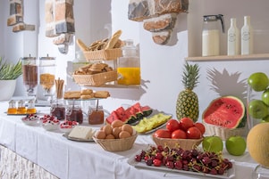 Un bufé de desayuno con diversas frutas, pan y bebidas.