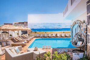 Una piscina al aire libre, sombrillas, sillones reclinables de piscina