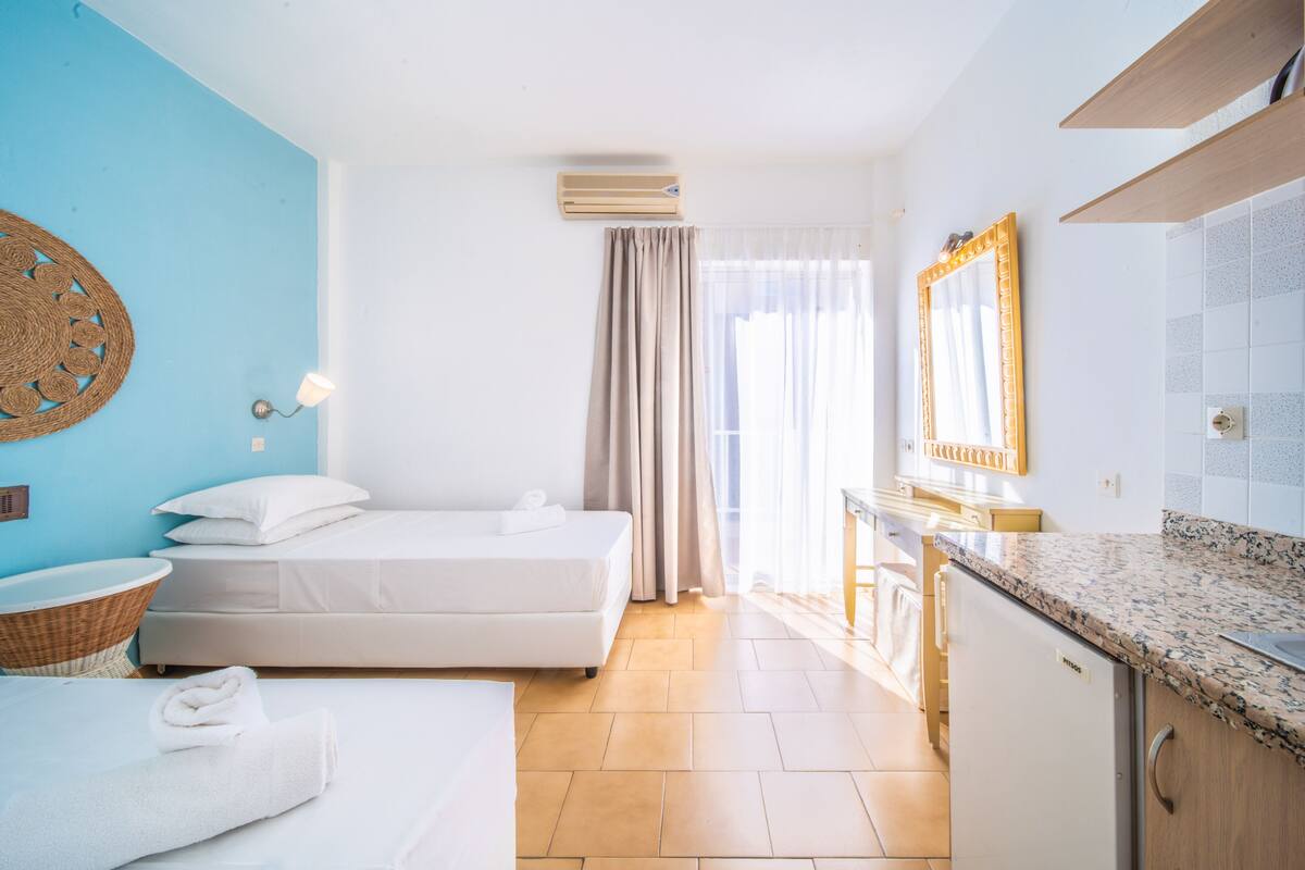 Una habitación de hotel con cama, lavamanos, espejo y ventana con cortinas.