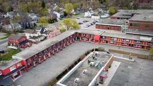 Ein Mehrstöckiges Hotel mit Innenhof, Sitzbereich im Freien und einem Parkplatz.