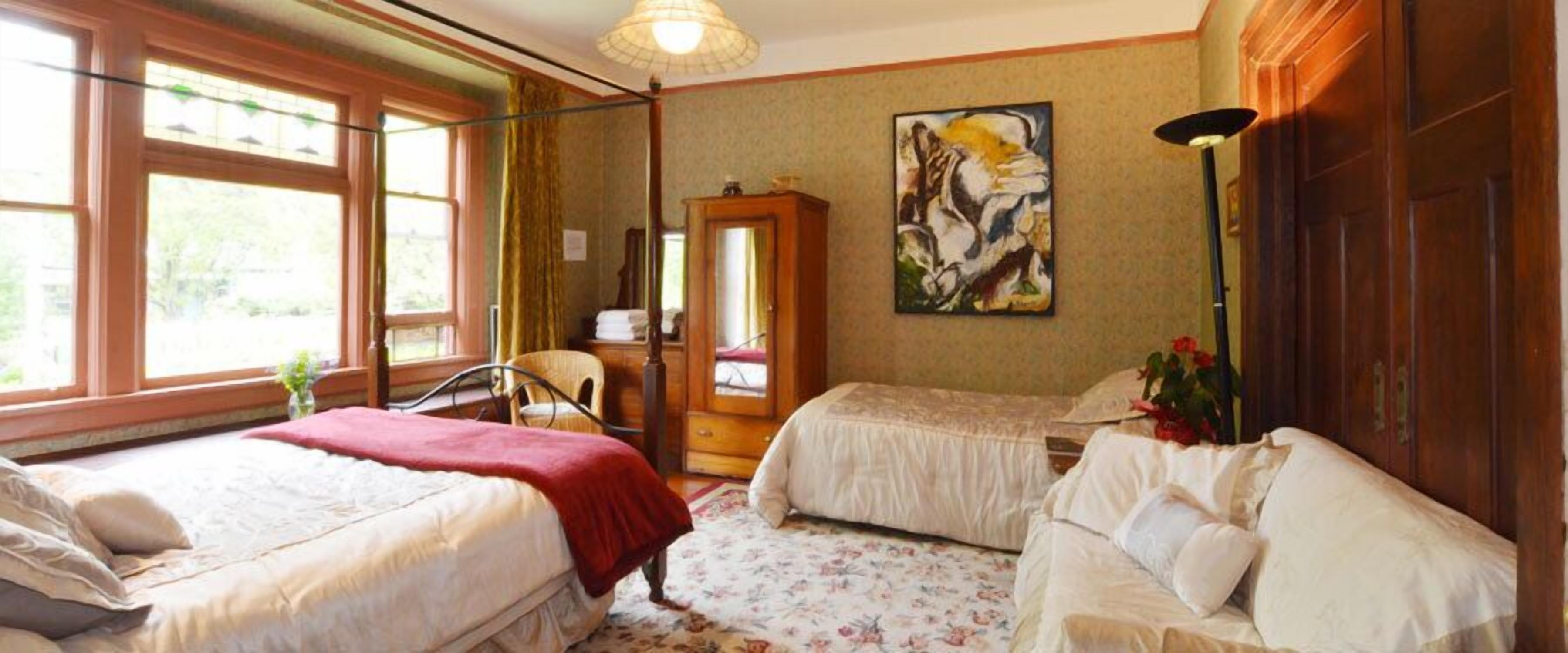 A room with two beds, a wooden cabinet, a painting, and a lamp.